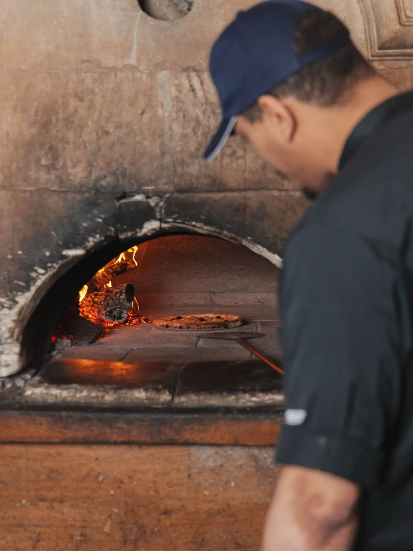 Une pizza cuit dans le four à bois de La Grotte